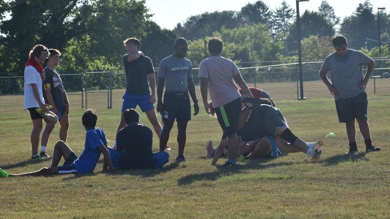 Male African American soccer coach discusses plays with team members during practice