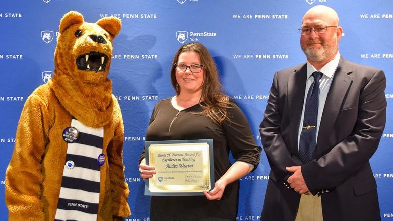 Nittany Lion character stands with female and male faculty members receiving an award