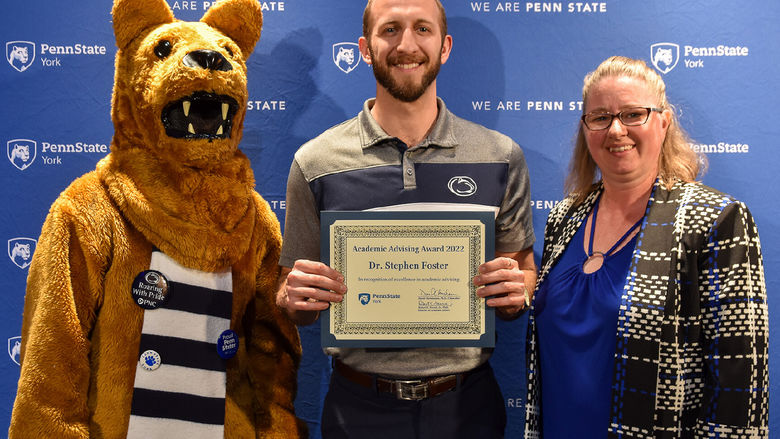 Nittany Lion character with a male and female faculty member with an award.