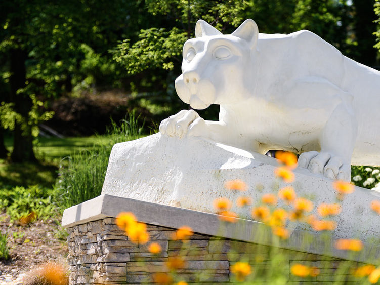 Nittany Lion Statue with spring flowers blooming.