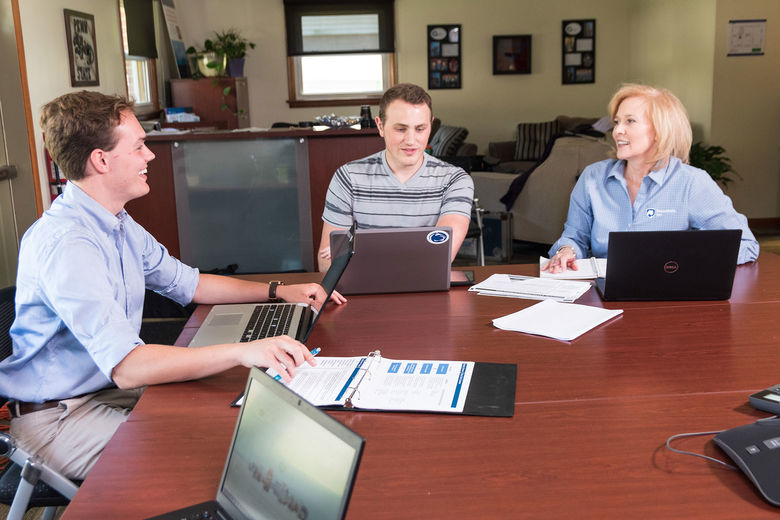 A faculty member and students meet at a conference table.