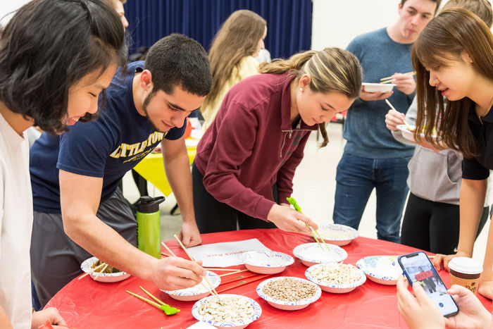 Students practice picking up rice with chopsticks during a Lunar New Year event.