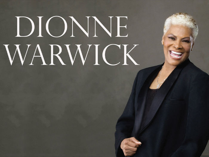 "Dionne Warwick" Woman wearing a black blazer, smiling confidently at the camera.