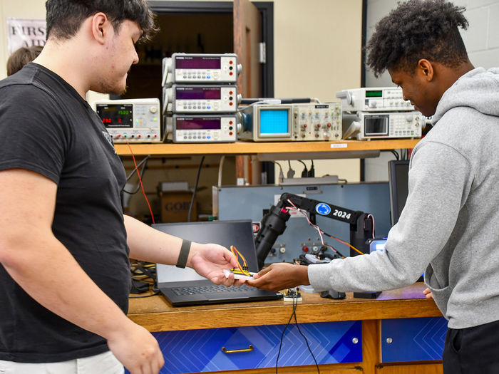 Two engineering students working on a remote arm prototype.