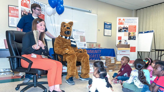 College students and the Nittany Lion mascot read to young children.