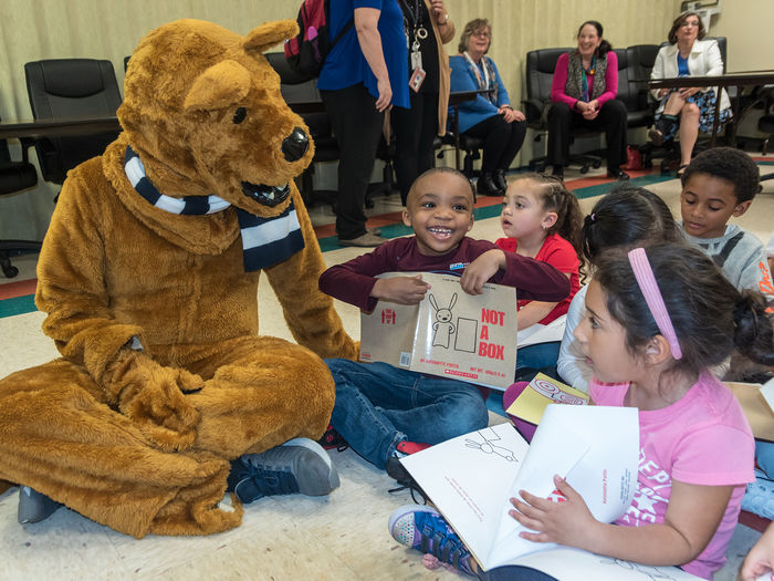 The nittany lion distributing books to children at a local book drive.