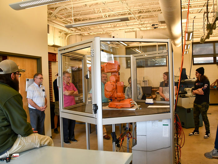 Students and faculty gathered around a robotic arm in the Swenson Engineering Center.