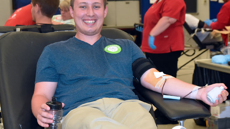 Smiling young caucasian male giving blood during a community blood drive.