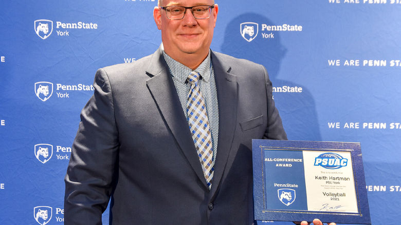 Adult male wearing glasses holding an award certificate.