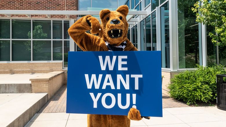 Nittany Lion holding a We Want You! sign.
