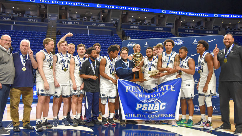 Penn State York men's basketball team celebrates with the championship banner and trophy.