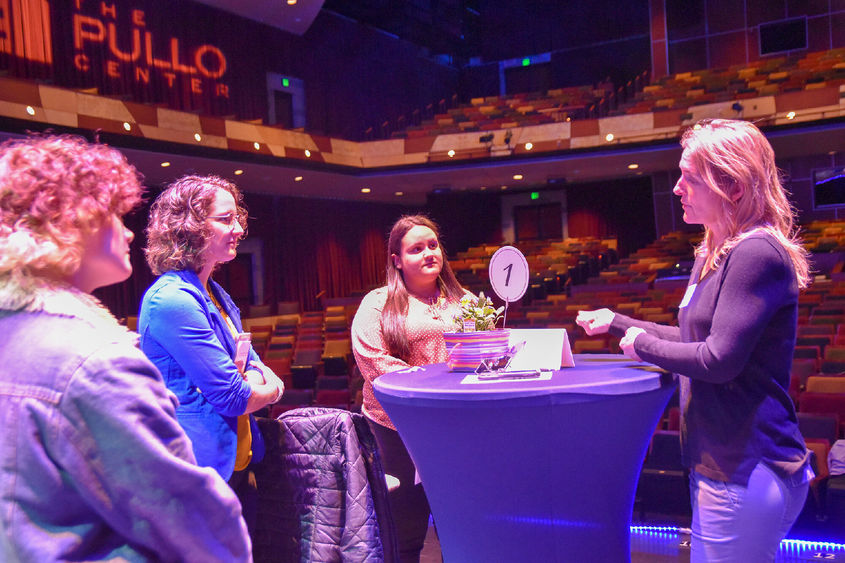 Three students interacting with business professional