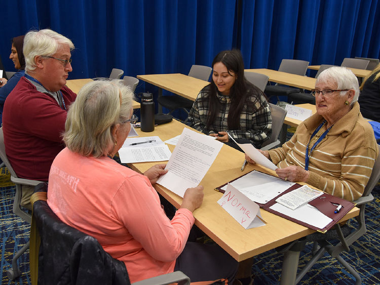 Three older adults, one male and two females, work with female student.