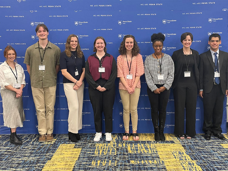 Eight student research award-winners  standing in fromt of a banner