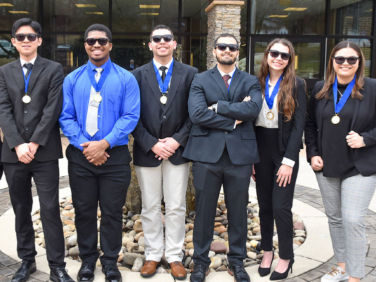 Four male and two femaile students wearing sunglasses in business attire