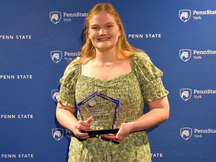 Female student with long blonde hair holding an athletic award.