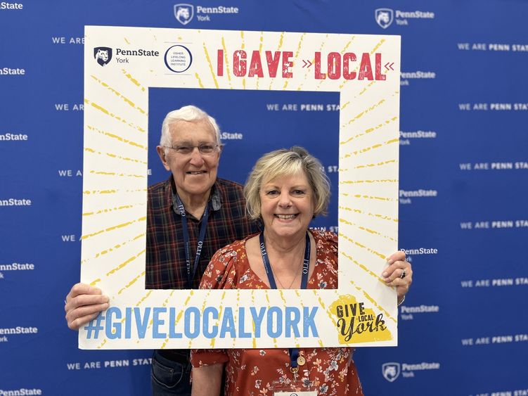Man and woman holding cutout sign for Give Local York.