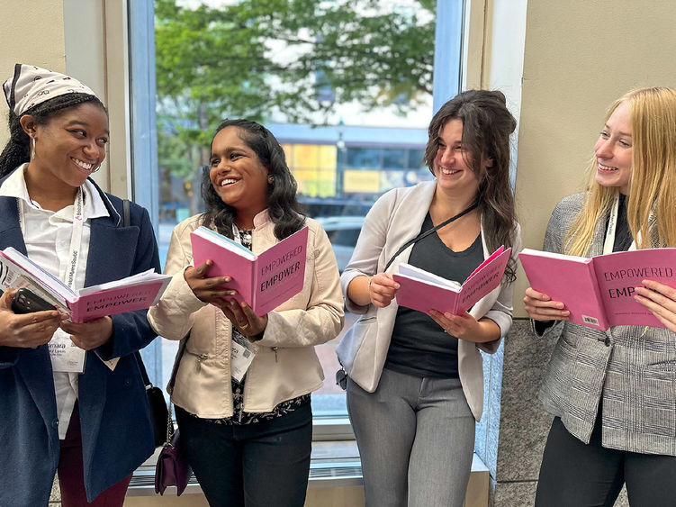 Four female students smile and hold pink journals they received as a gift from the Women's Philanthropic Network (WPN) at Penn State York